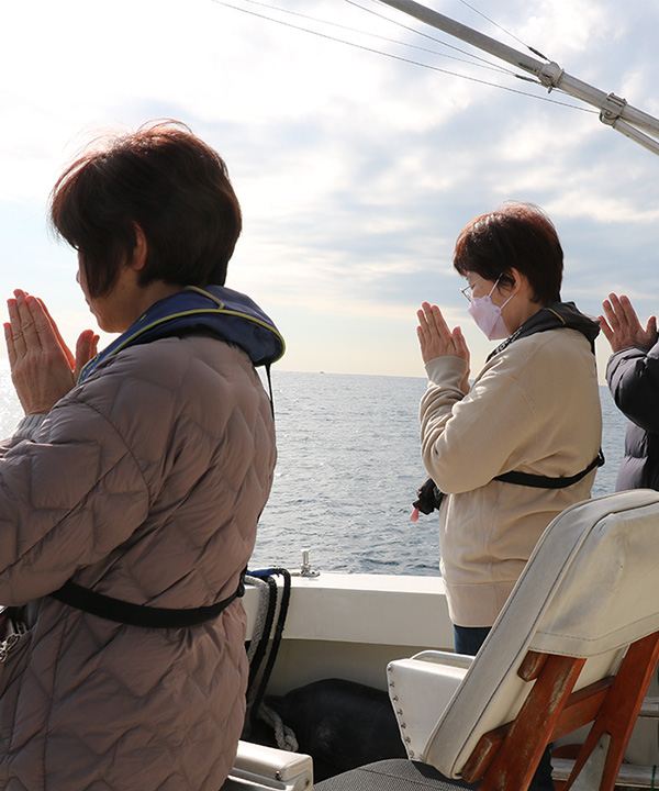 海に向かい手を合わせている女性