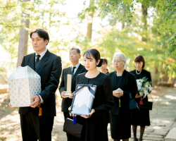 ご家族が遺骨や遺影を歩きながら運んでいる様子