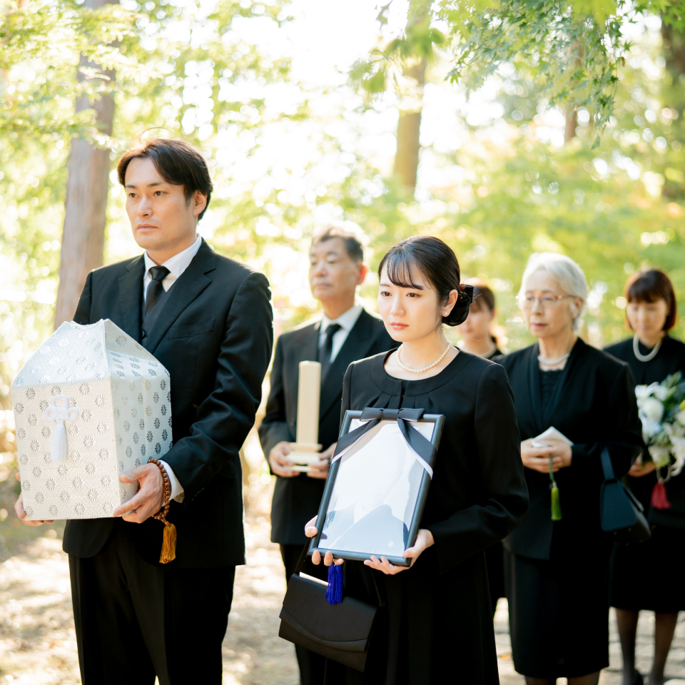 ご家族が遺骨や遺影を歩きながら運んでいる様子
